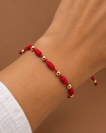 Pulsera 7 nudos roja con oro, puesta