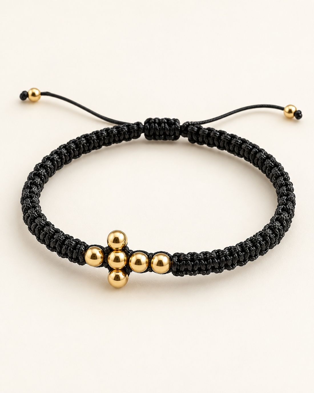 Pulsera tejida negra con cruz de balines de oro, foto 1 de 2