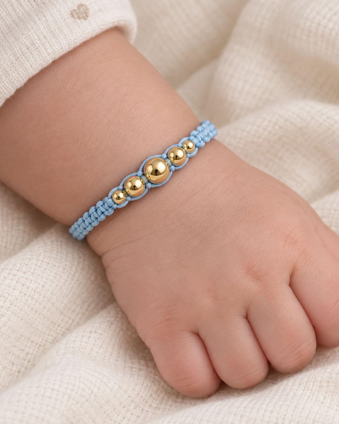 Pulsera de balines de oro 14k, cordón celeste, puesta en la muñeca