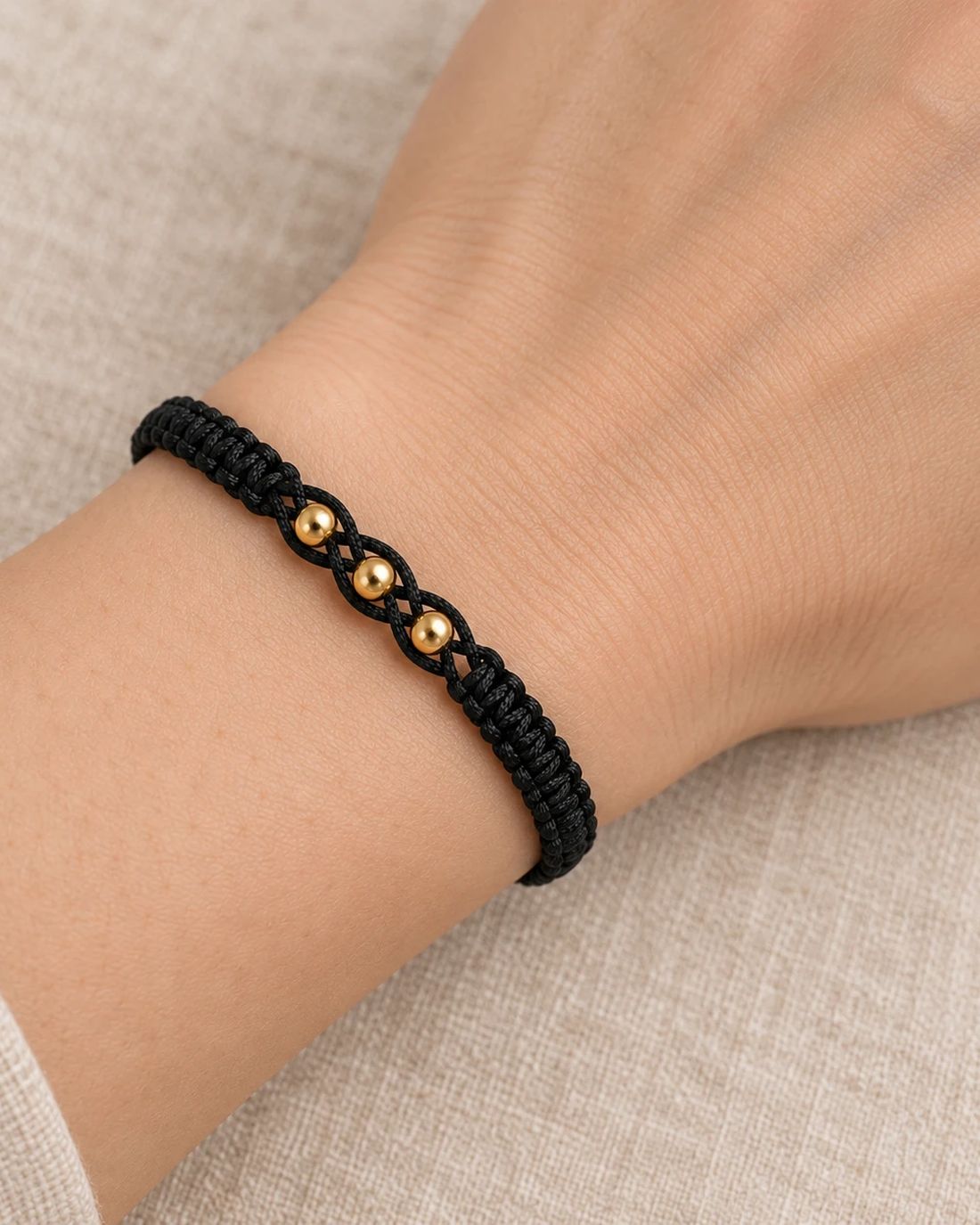 Pulsera hilo negro con balines de oro 14k, puesta en la muñeca