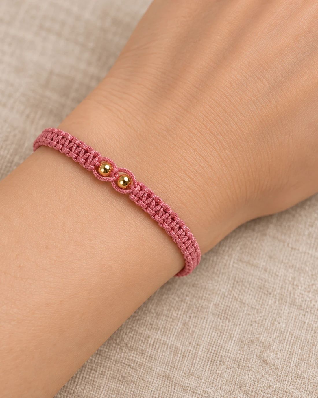 Pulsera hilo rosa con balines de oro 14k, puesta en la muñeca