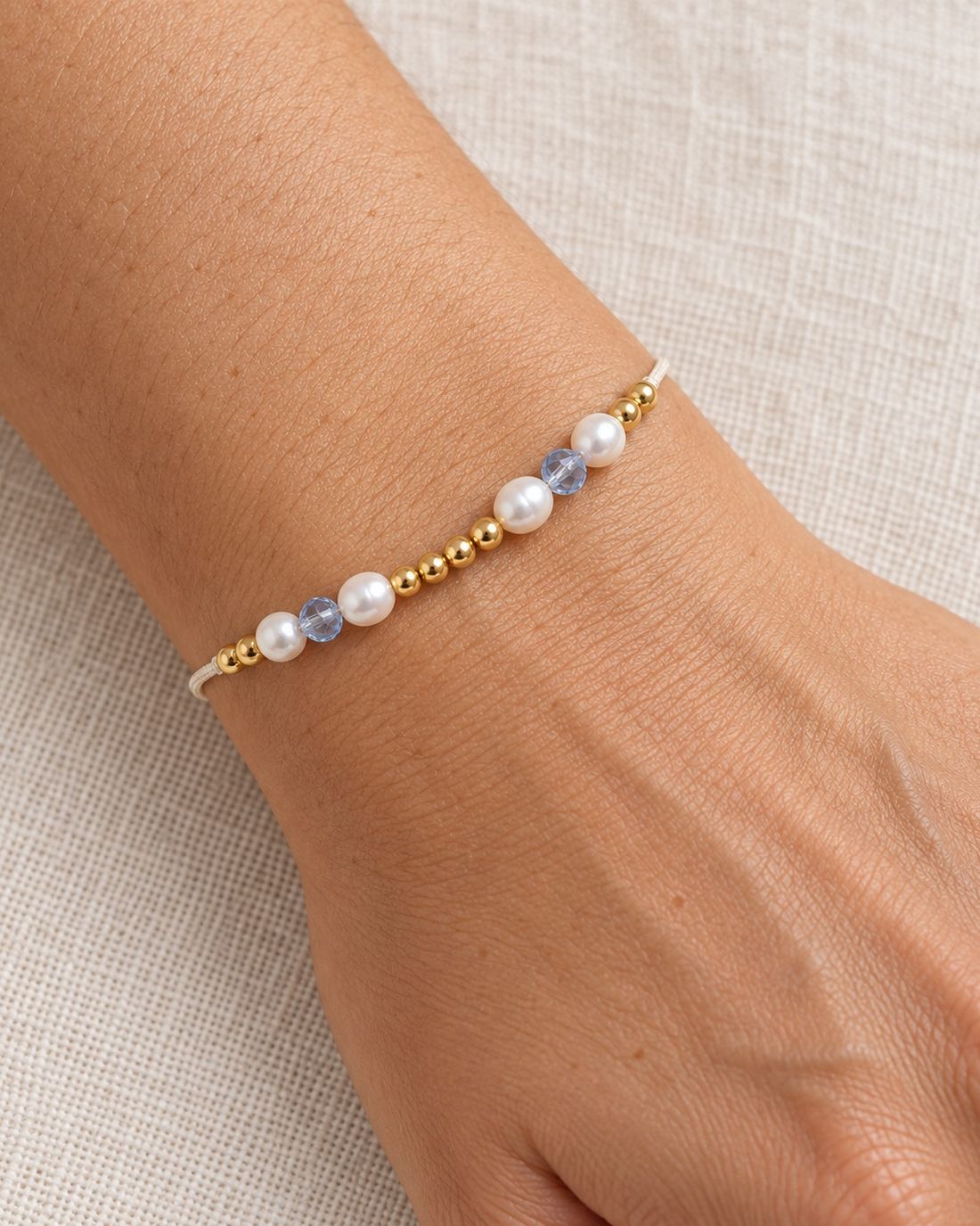Pulsera de perlas con balines de oro 14k, puesta en la muñeca